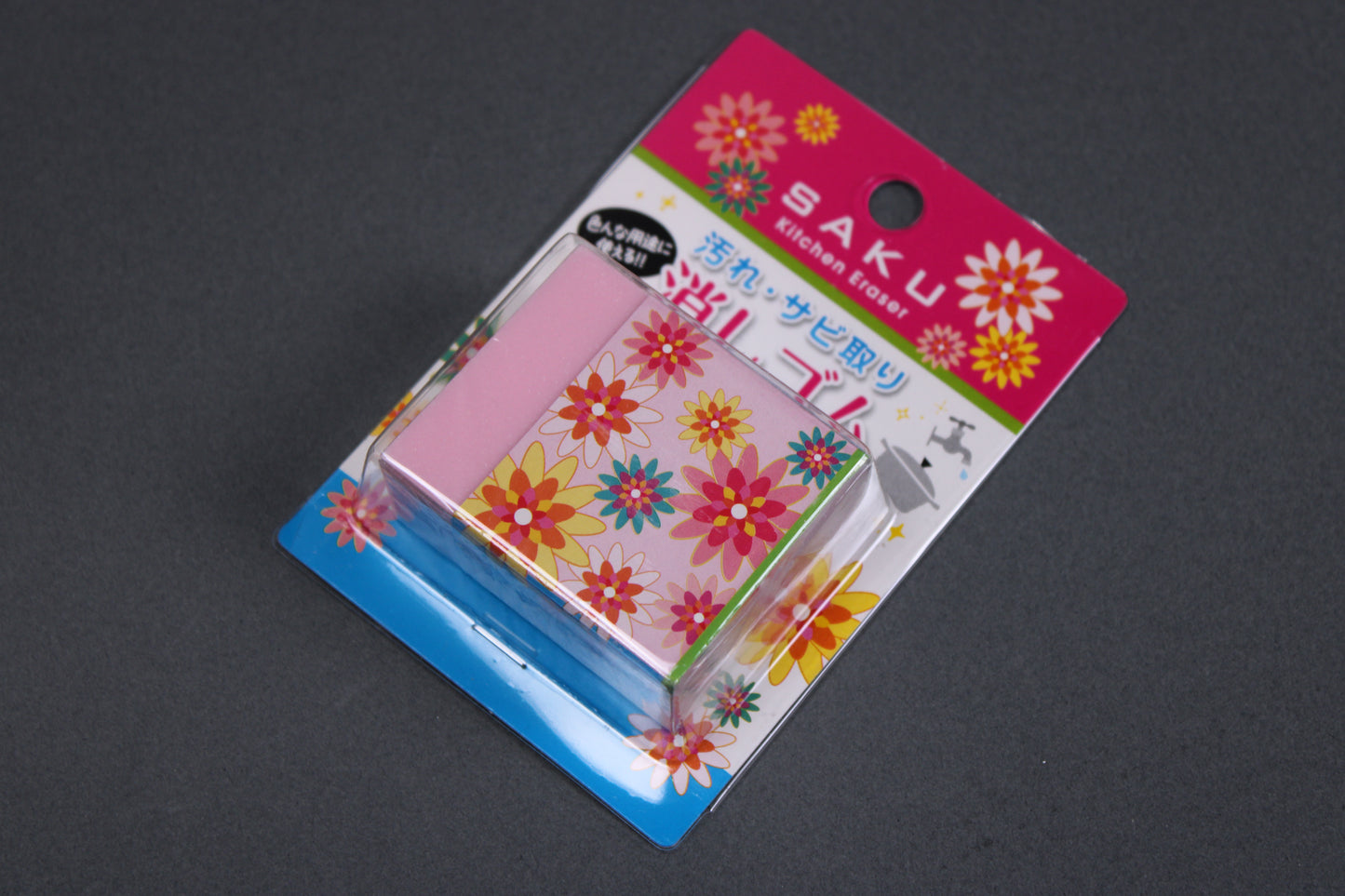 pink block shaped rust eraser partially wrapper in thick paper cover with multicolored star flower shapes in product package with Saku