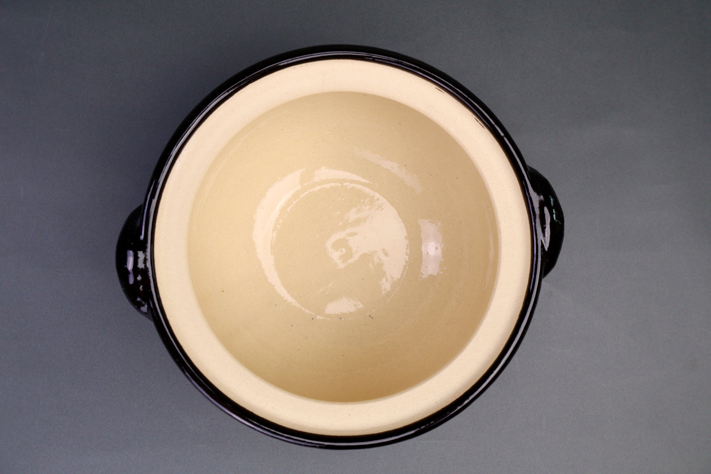 black glazed and clear glazed two lidded rice cooker tilted to see clear shiny interior in grey backdrop