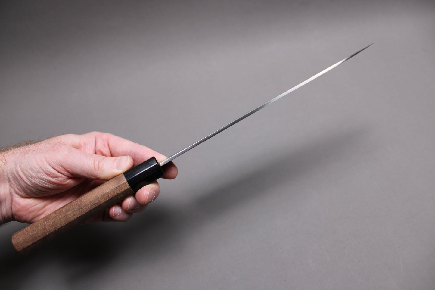 hand holding knife top spine of knife distal tapering