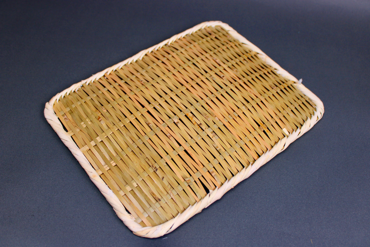 woven bamboo strainer rectangular tan brownish in color with grey blue backdrop
