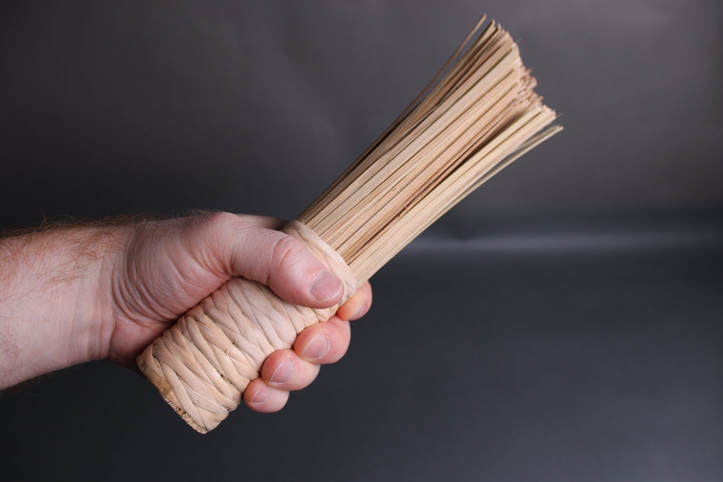 extra wide stout shot bamboo wok brush by chan chi kee for quick cleaning held I hand at angle on grey background