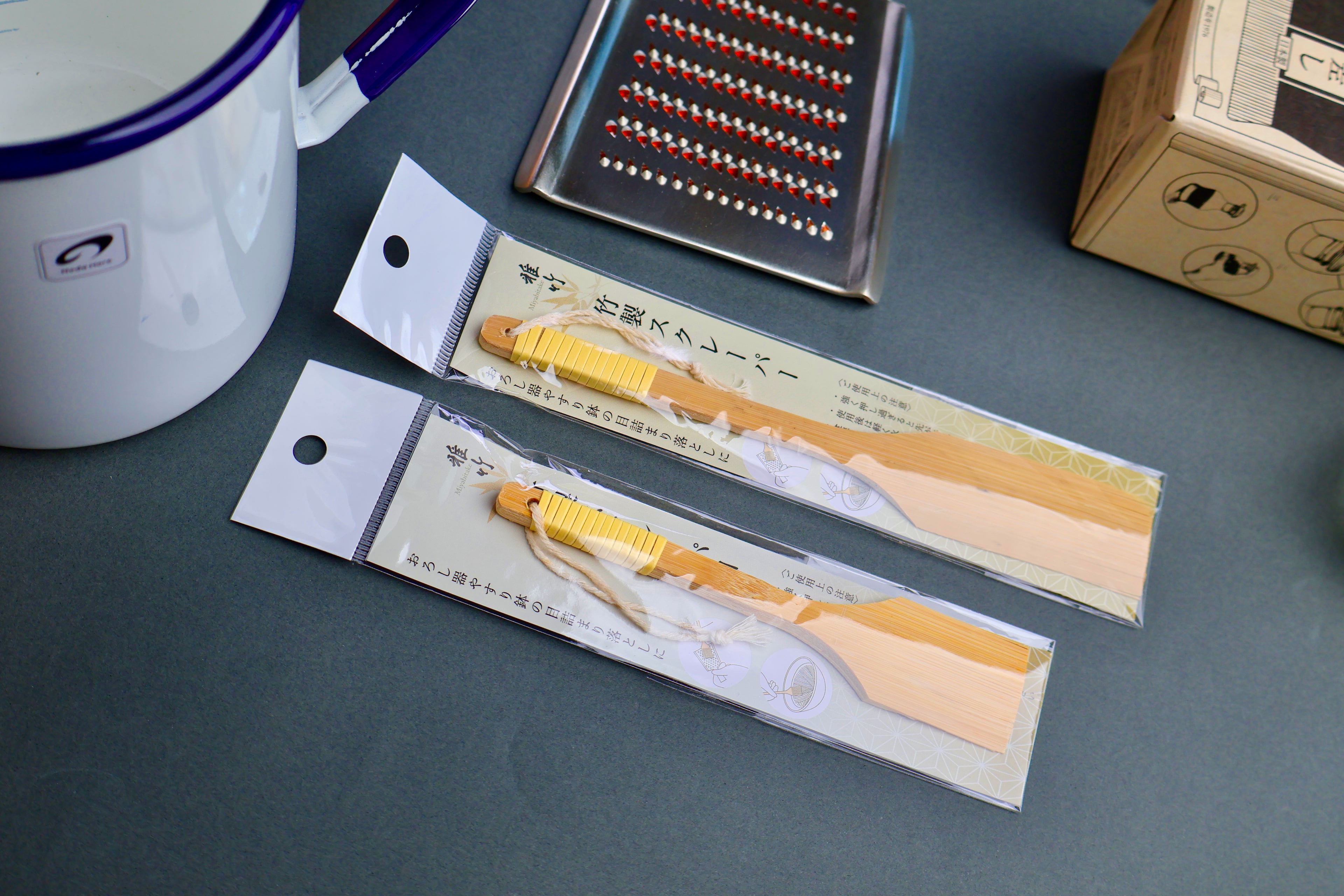 Two yellow chasen in packaging on a gray surface with a mug and small box in the background.