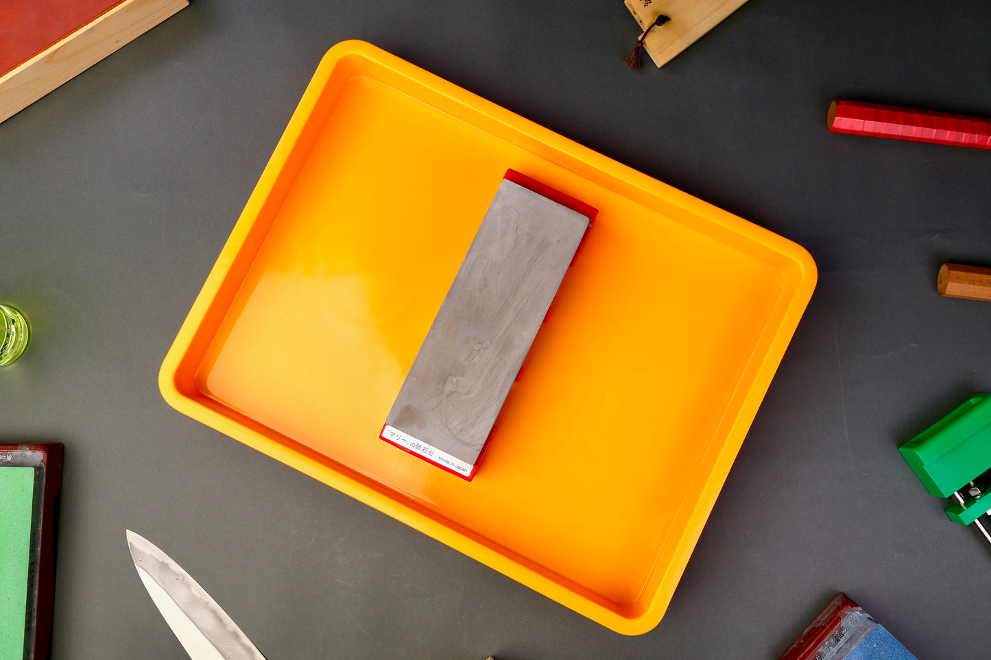 yellow orange short box with morihei whetstone on holder inside surrounded by japanese knife accessories