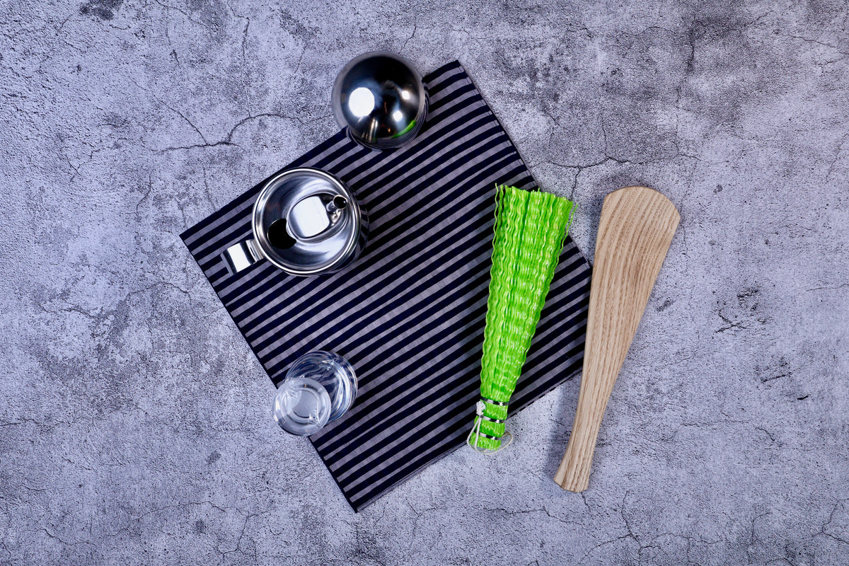 Hamamonyo tateyoko striped tenugui styled on concrete with kitchen tools, showing real-use context