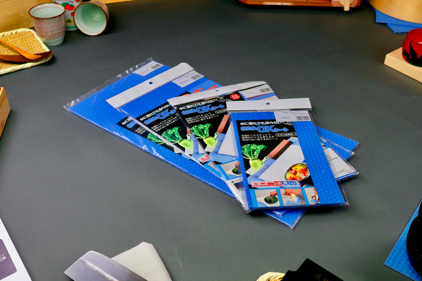 four different sizes bright blue rectangular shaped plastic wrapped rubber non slip its with brightly colored product paper on gray background