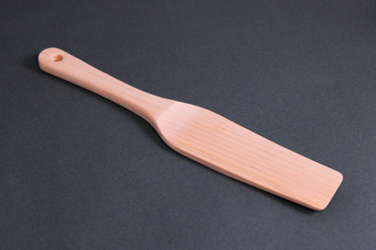 small hinoki wood spatula long thin handle and  slightly larger broad spatula area on dark grey surface
