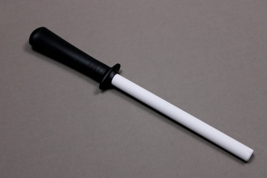 plastic black handled white ceramic honing rod angled on grey background