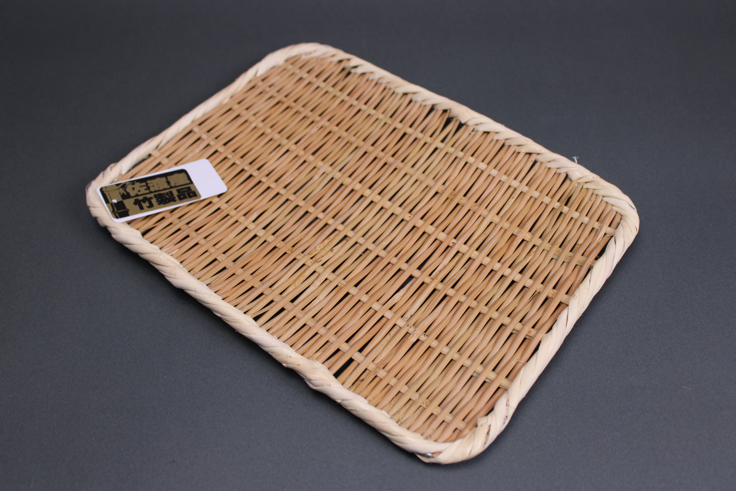 bright brown woven bamboo plate from Sado Japan with grey background