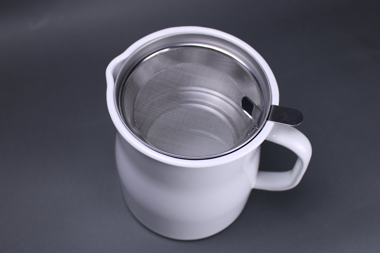 top down image of noda horo oil pot storage white glazed container with aluminum insert to hold oil strainer and filter made in japan there is a grey background contrasting the products bright color