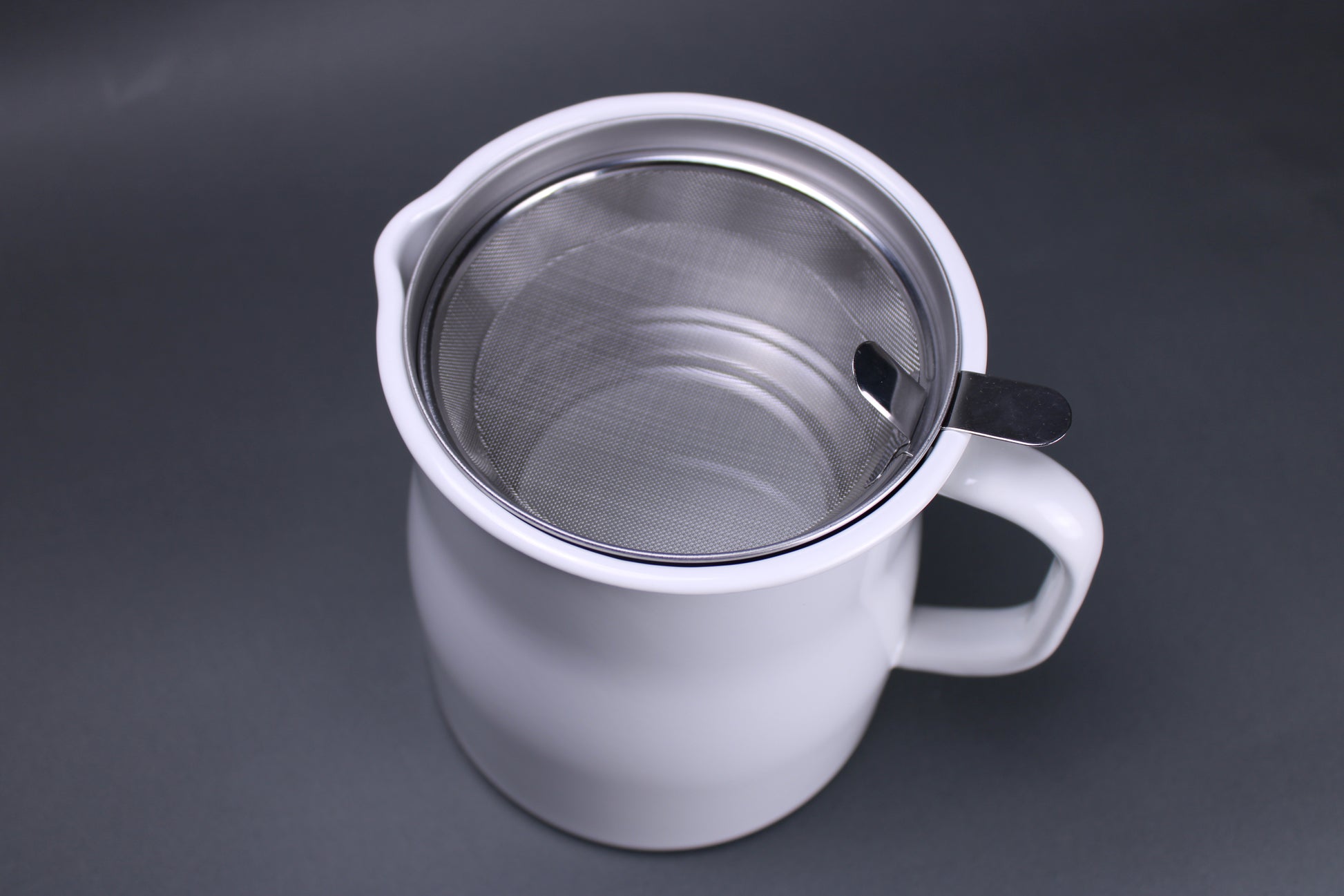 top down image of noda horo oil pot storage white glazed container with aluminum insert to hold oil strainer and filter made in japan there is a grey background contrasting the products bright color