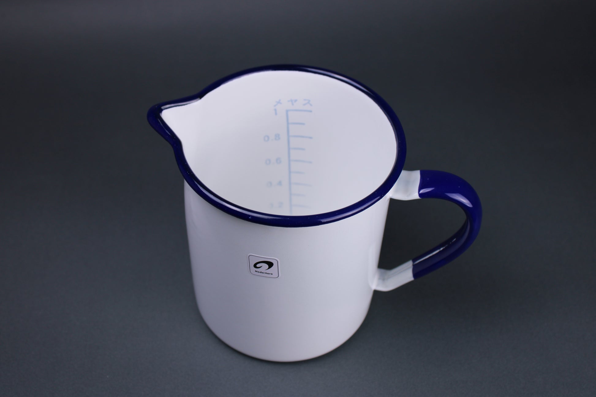 top down view of one liter measuring cup with measuring marks and numbers printed inside brand label sticker on outside of body with grey background