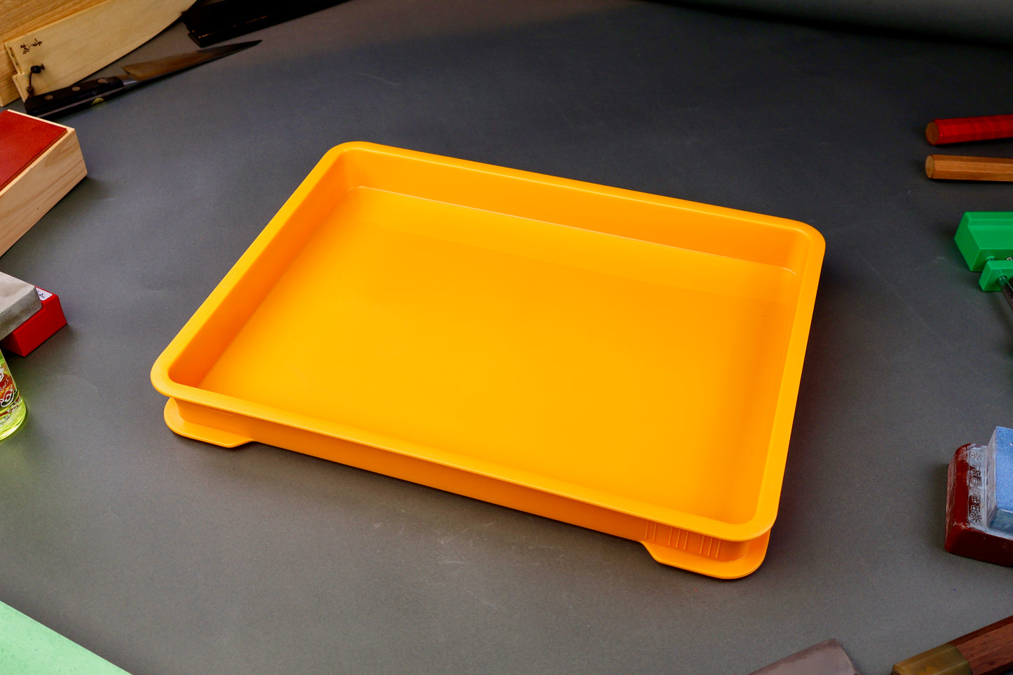 low wide yellow knife sharpening box from Japan surrounded by knife sharpening accessories grey background