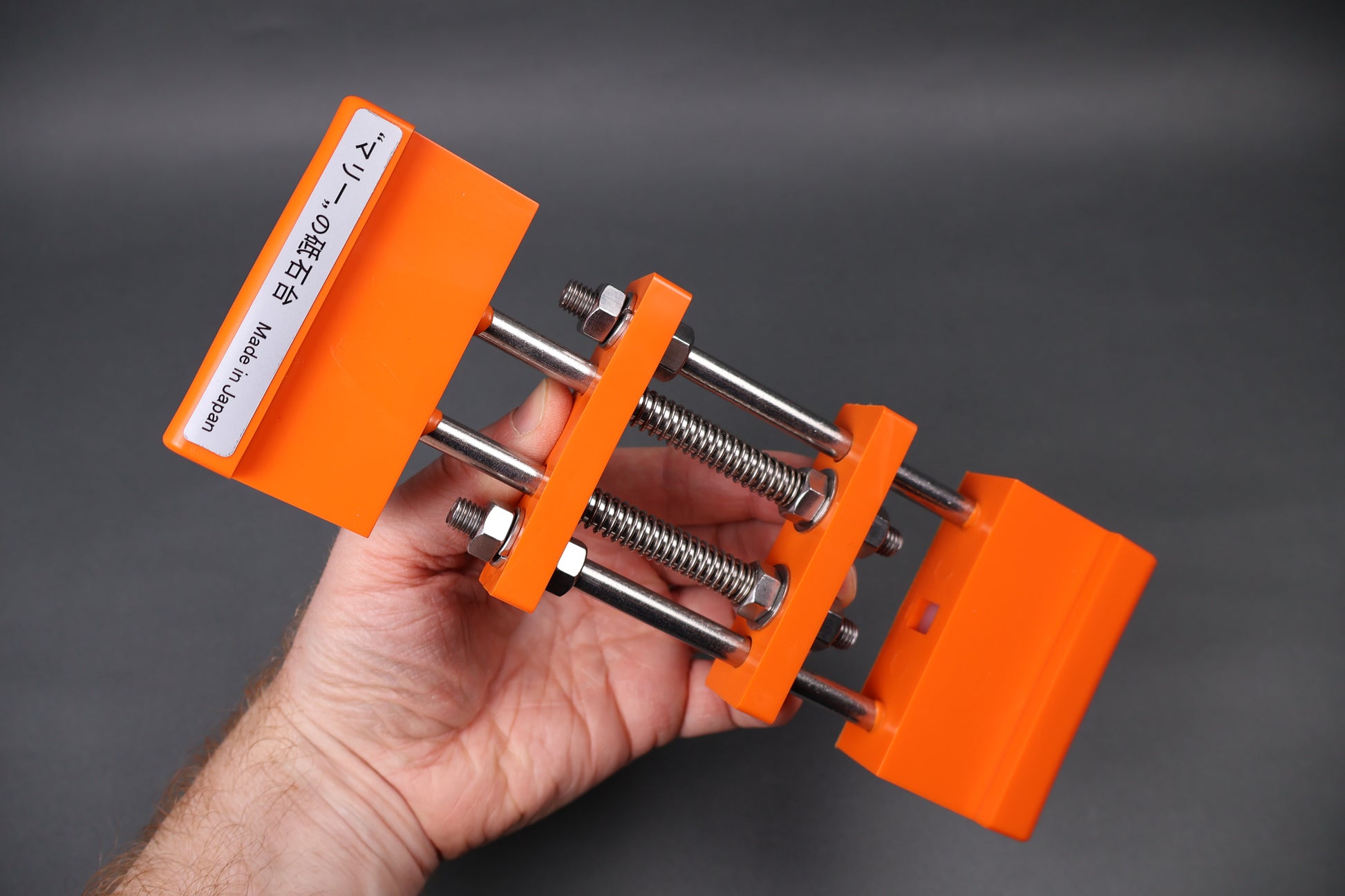 hand holding whetstone holder orange spring loaded grey background