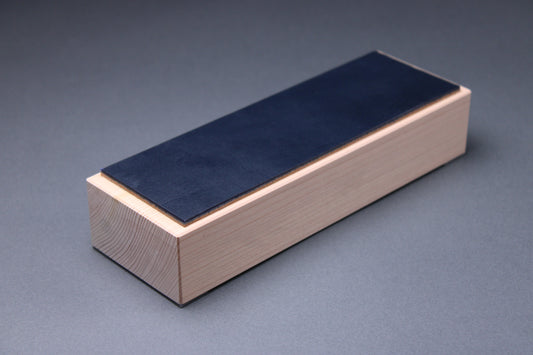 english bridle leather knife strop colored midnight blue mounted to tall hinoki wood yoshino base with smooth sides showing tree rings with light grey background profile shot