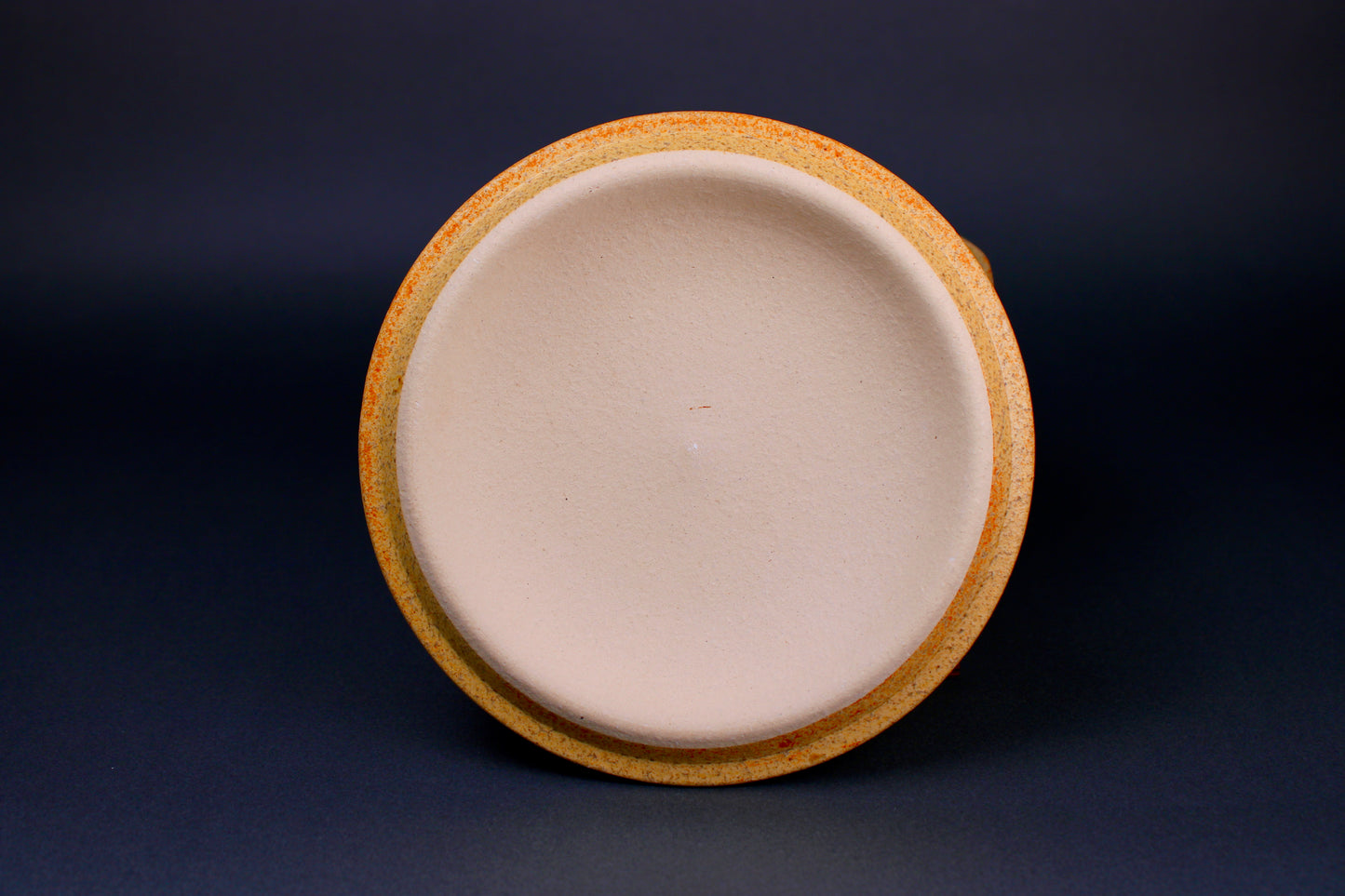 round yellowish lid with white center standing in grey background