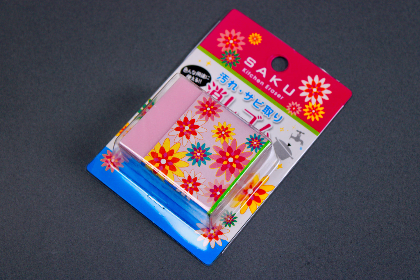 naniwa rust eraser in pink blue and white packaging showing floral paper partially wrapped around pink rust eraser in grey backdrop