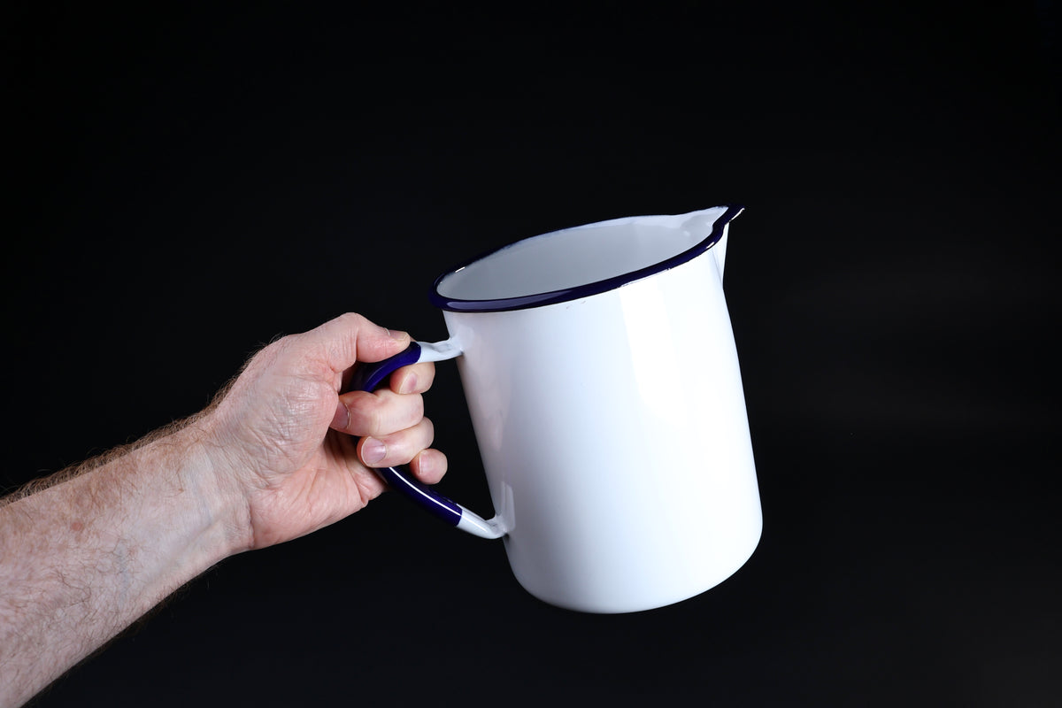 Noda Horo enamel measuring pitcher 2L — held by cobalt blue handle showing full side profile and size