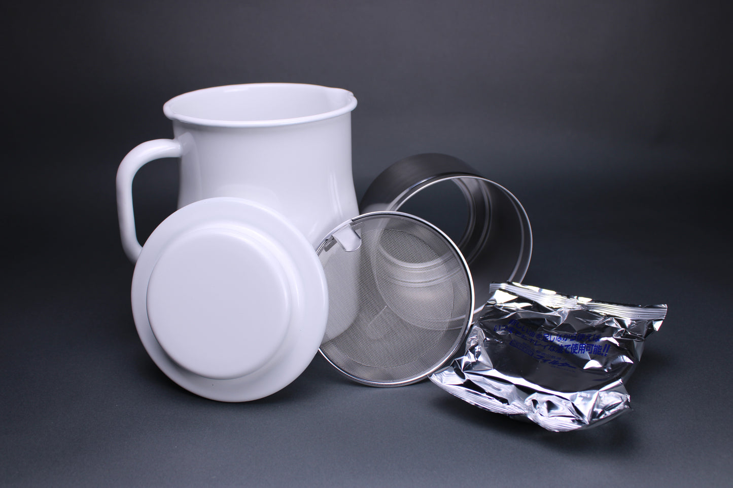 frontal product image showing all the accessories including the white glazed oil pot white glazed deep curved lid insert piece and filter screen and carbon filter to strain oil there is a grey background contrasting the products