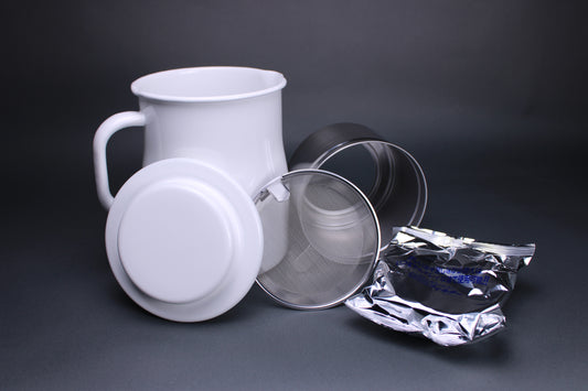 frontal product image showing all the accessories including the white glazed oil pot white glazed deep curved lid insert piece and filter screen and carbon filter to strain oil there is a grey background contrasting the products