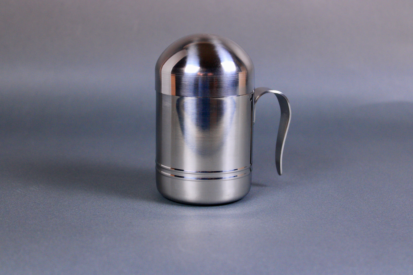 steel cooking oil container shaped cylinder with curved handle grey background