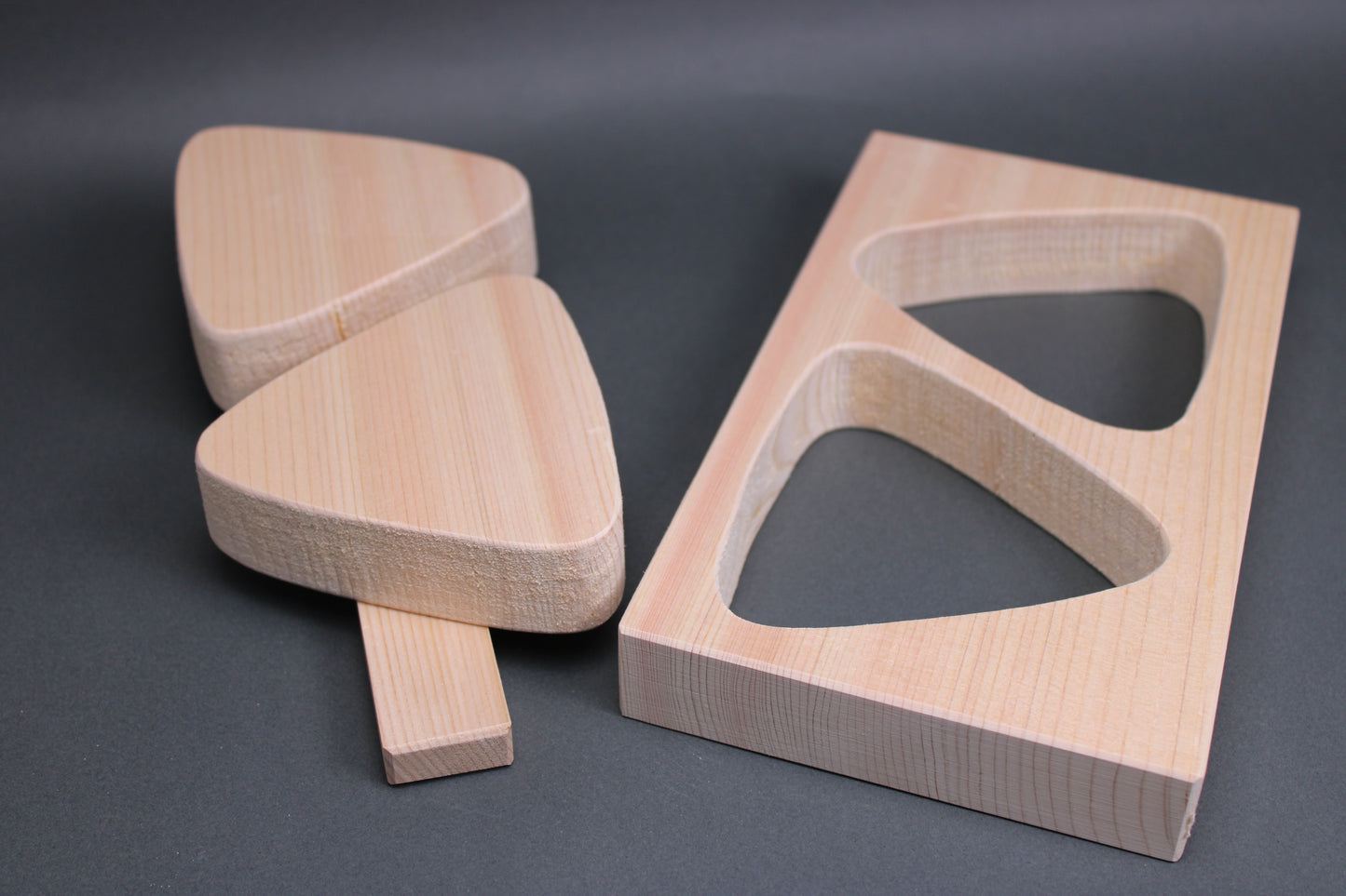 rectangular light tan hinoki wood onigiri maker two large triangles horizontal connecting wood nailed in place in dark backdrop