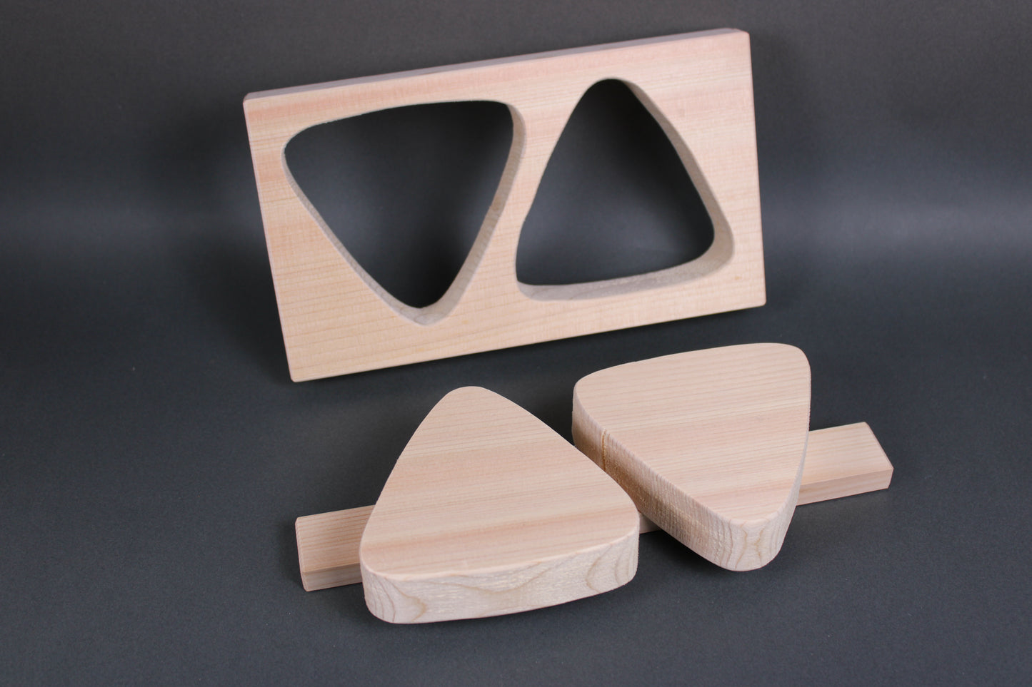 rectangular light tan hinoki wood onigiri maker two large triangles horizontal connecting wood nailed in place in dark backdrop