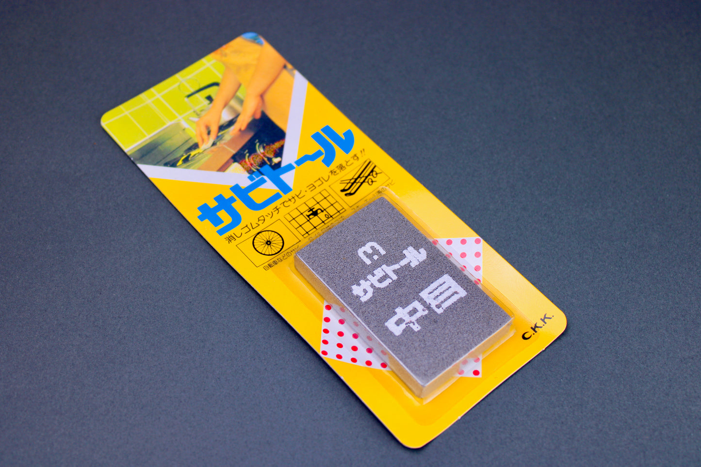 rectangular yellow packaging for gray rust eraser with white kanji print on grey background