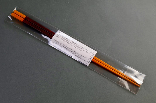 Pair of urushi bamboo saibashi chopsticks in clear packaging on a gray background