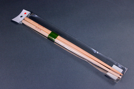 Pair of hinoki wooden chopsticks in clear packaging on a dark gray background