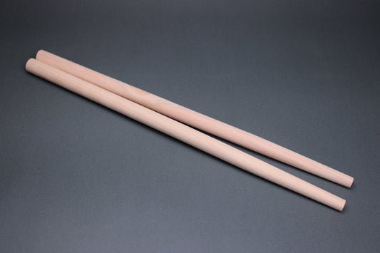 long thick round hinoki wood cooking chopsticks sit parallel on dark grey background