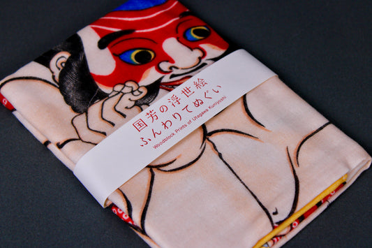 rectangular packaged tenugui towel printed with blue red tan black classical japanese warrior on dark backdrop