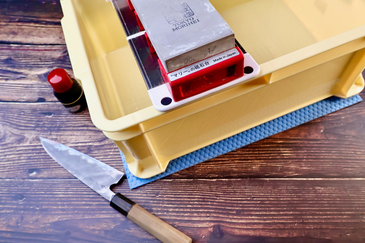 Sharpening station kit tall — stone holder in tray with whetstone, Japanese knife, and tsubaki oil in use