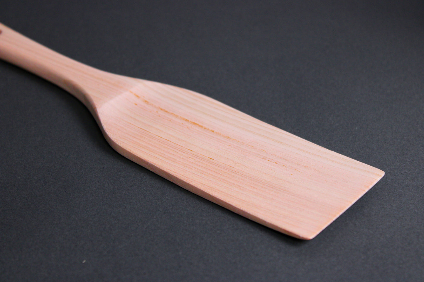hinoki wood spatula long wide with thin handle and broad spatula area on dark grey surface