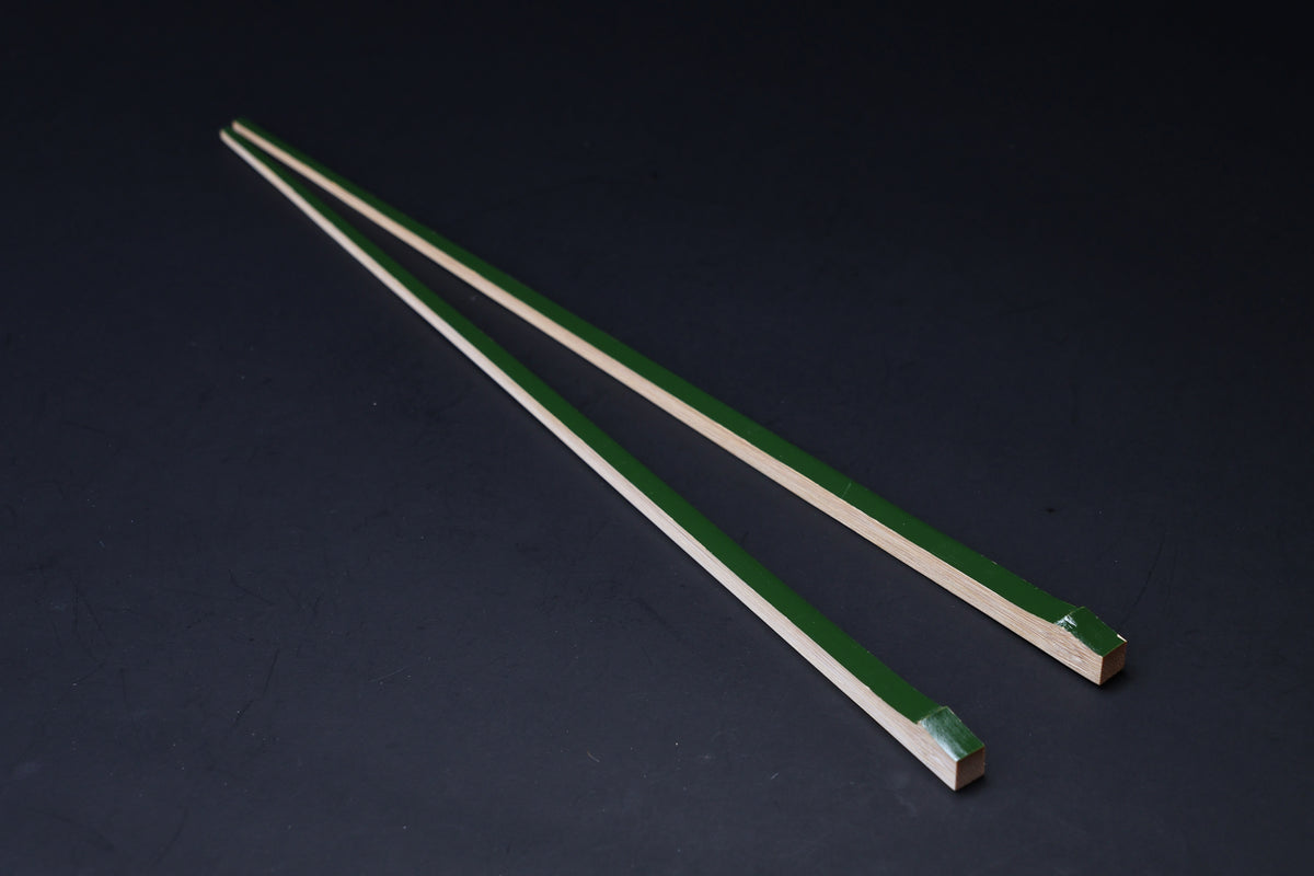 Tenbushi dark green bamboo chopsticks angled on black, square lacquered ends and tapered natural bamboo tips visible