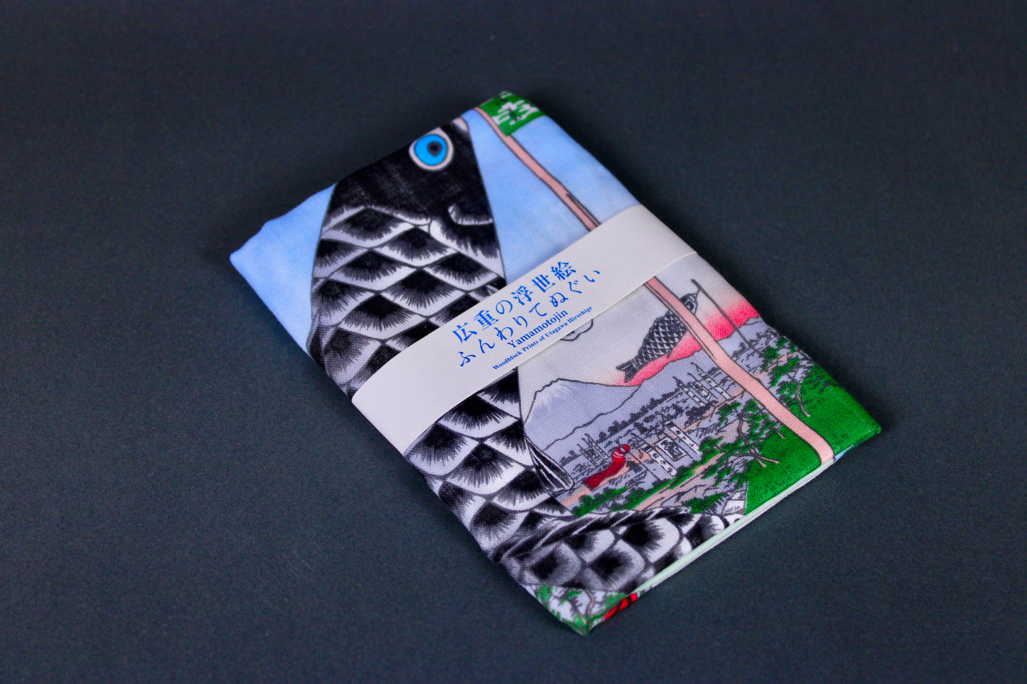 rectangular packaged tenugui towel printed with light blue red black green classical japanese carp on dark backdrop