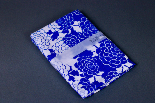 rectangular packaged tenugui towel printed with blue white classic floral pattern on dark backdrop