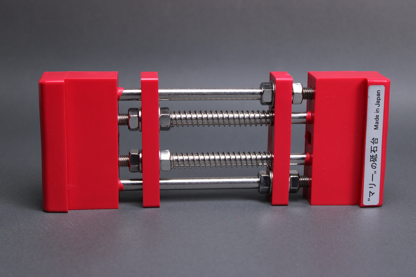 marie whetstone holder red rectangular shaped on its side showing red pvc body stainless steel rods springs grey backdrop