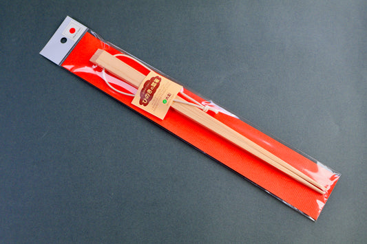 Pair of wooden rectangular hinoki cooking chopsticks in a clear plastic package with a red backing on a gray background
