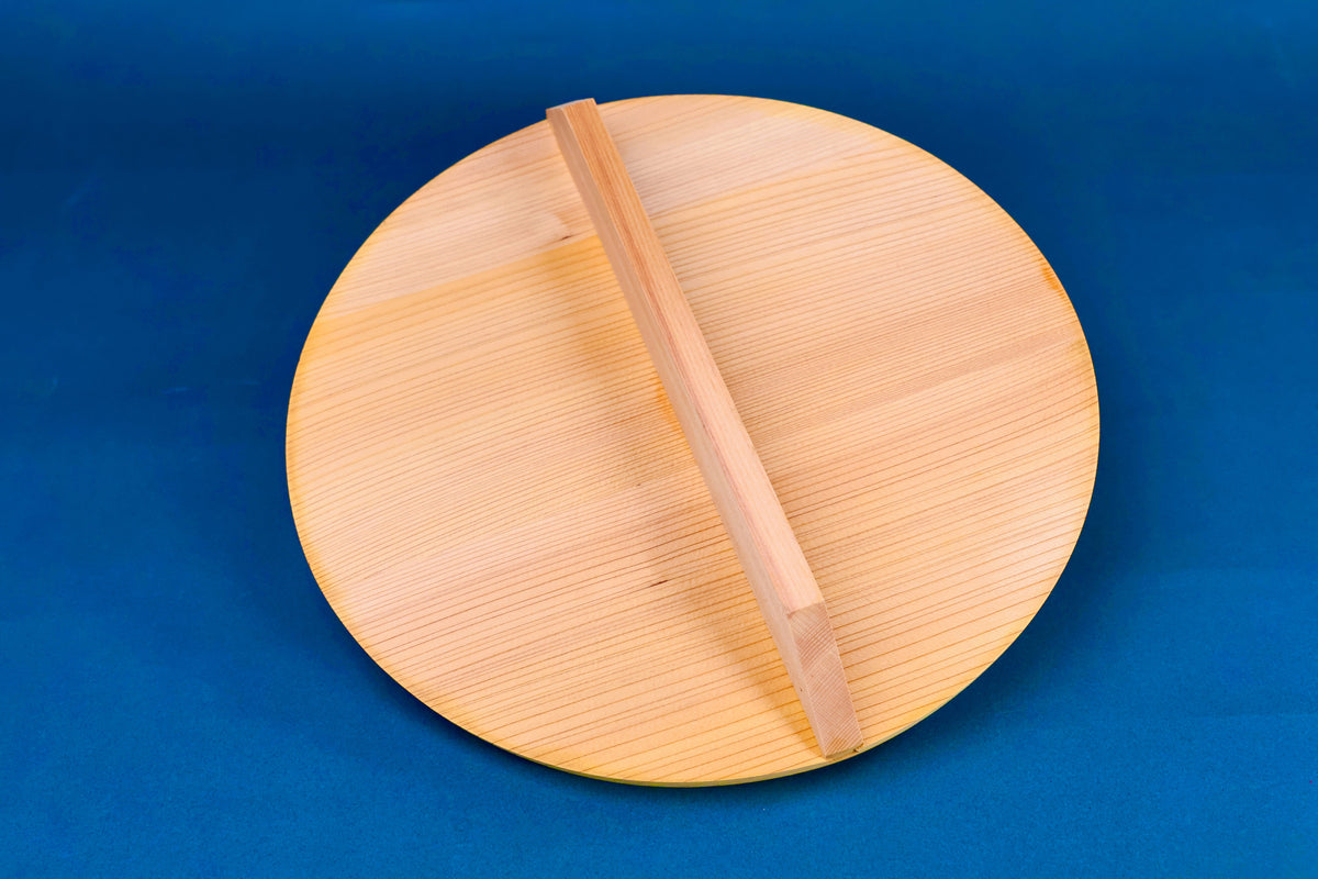 wooden drop lid for stewing and braising to fit inside pot for tender food inside aluminum two handled pot surrounded by kitchenware 