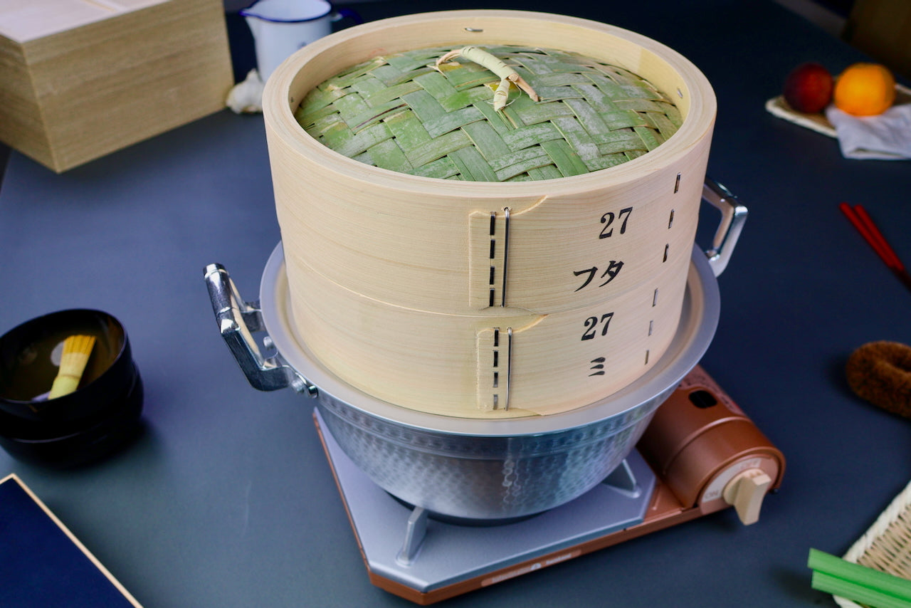 round hinoki wood bamboo steamer on aluminum pot on portable butane stove surrounded by japanese kitchenware