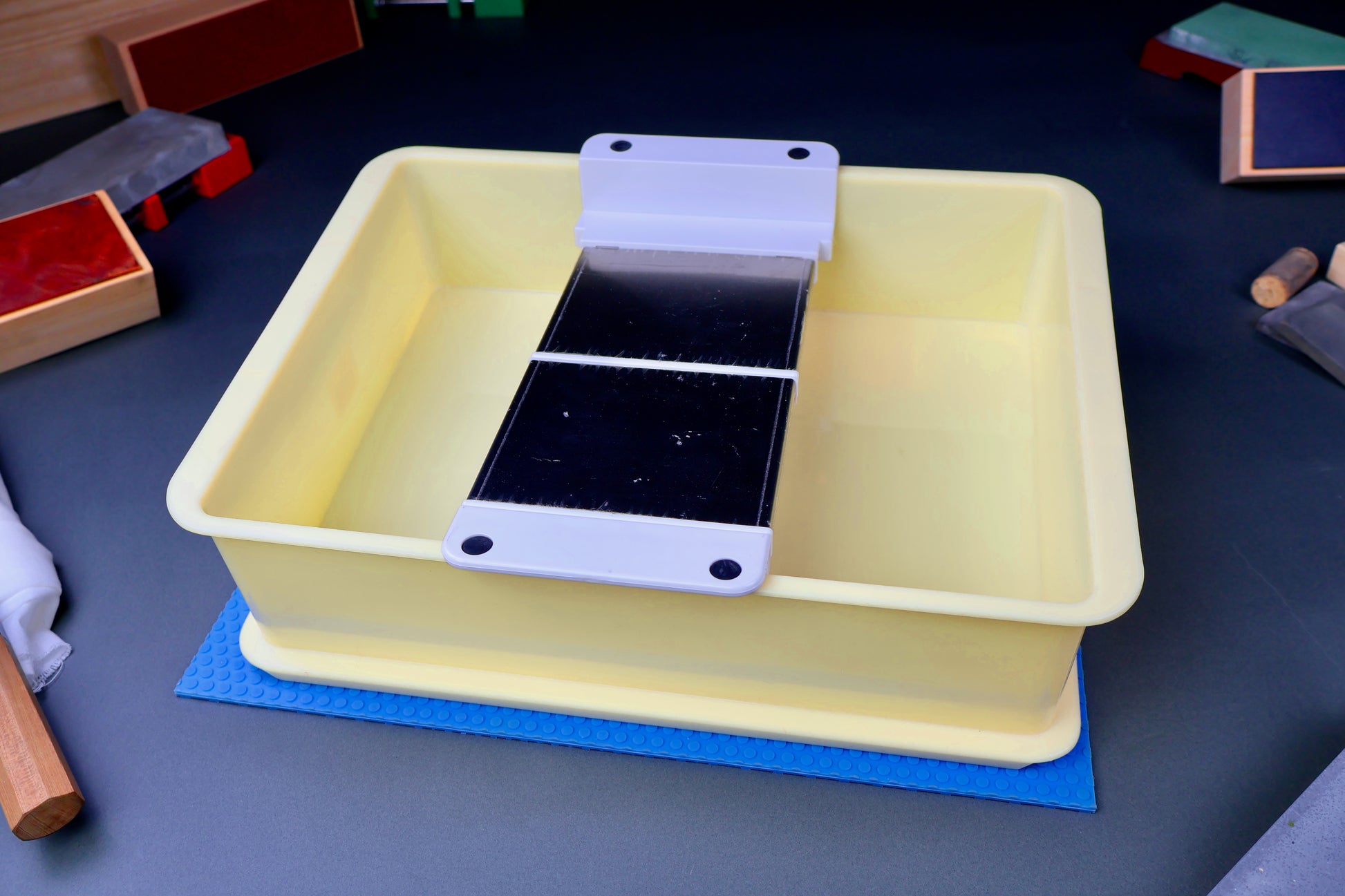 frontal shot of suehiro multi rack sitting inside yellowish box atop hasegawa non slip mat surrounded by knife accessories 
