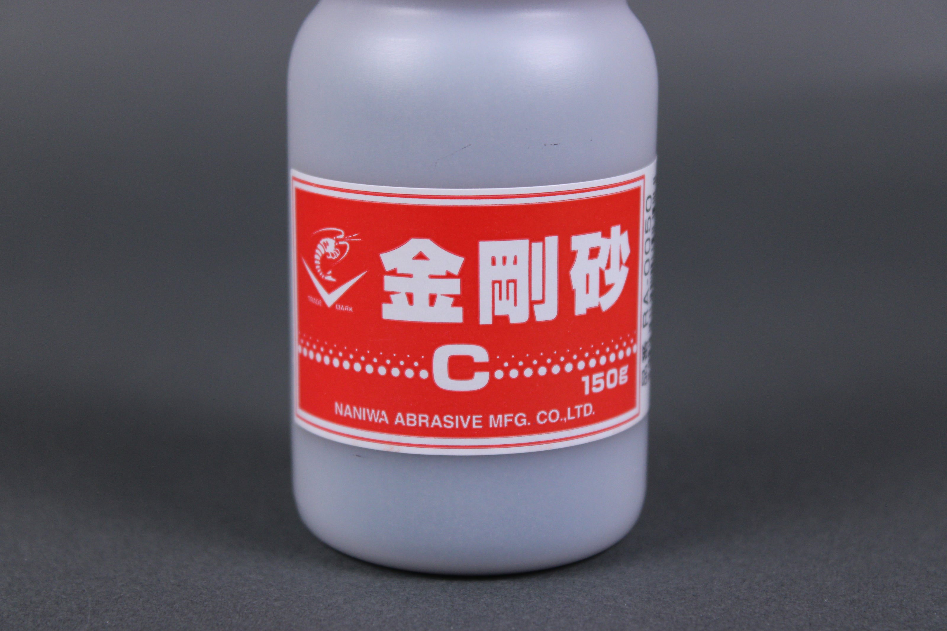 detailed close up shop of Naniwa abrasive powder c red white product logo sticker dark grey background