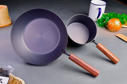 detailed closeup shot of two nitride iron pans angled up with brown wooden handles surrounded by Japanese kitchenware grey background
