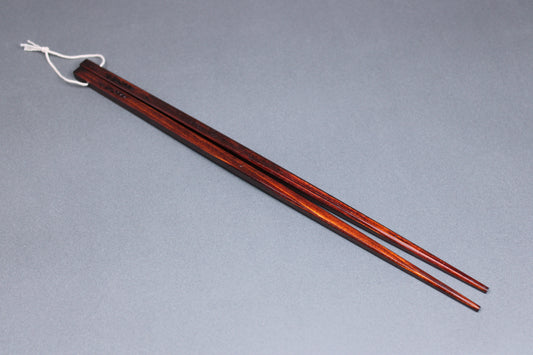 angled shot of hinoki wood saibashi cooking chopsticks with string attaching on light grey backdrop