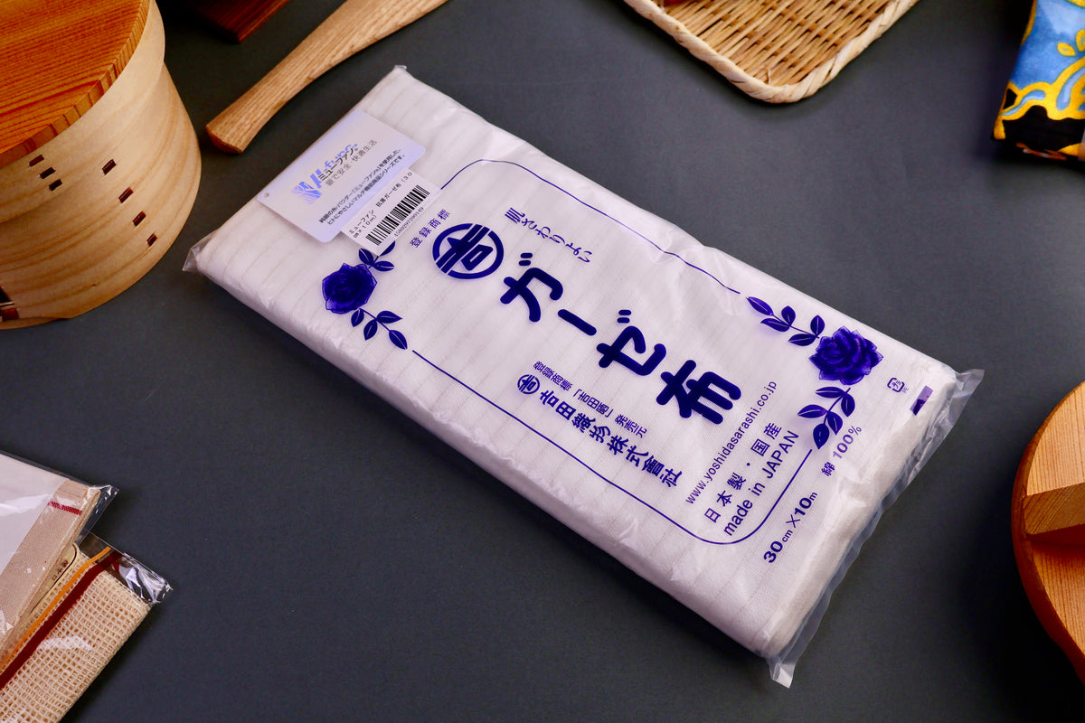 Yoshida sarashi gauze towel woven with silver strands in clear plastic packaging surrounded by japanese kitchenware grey background