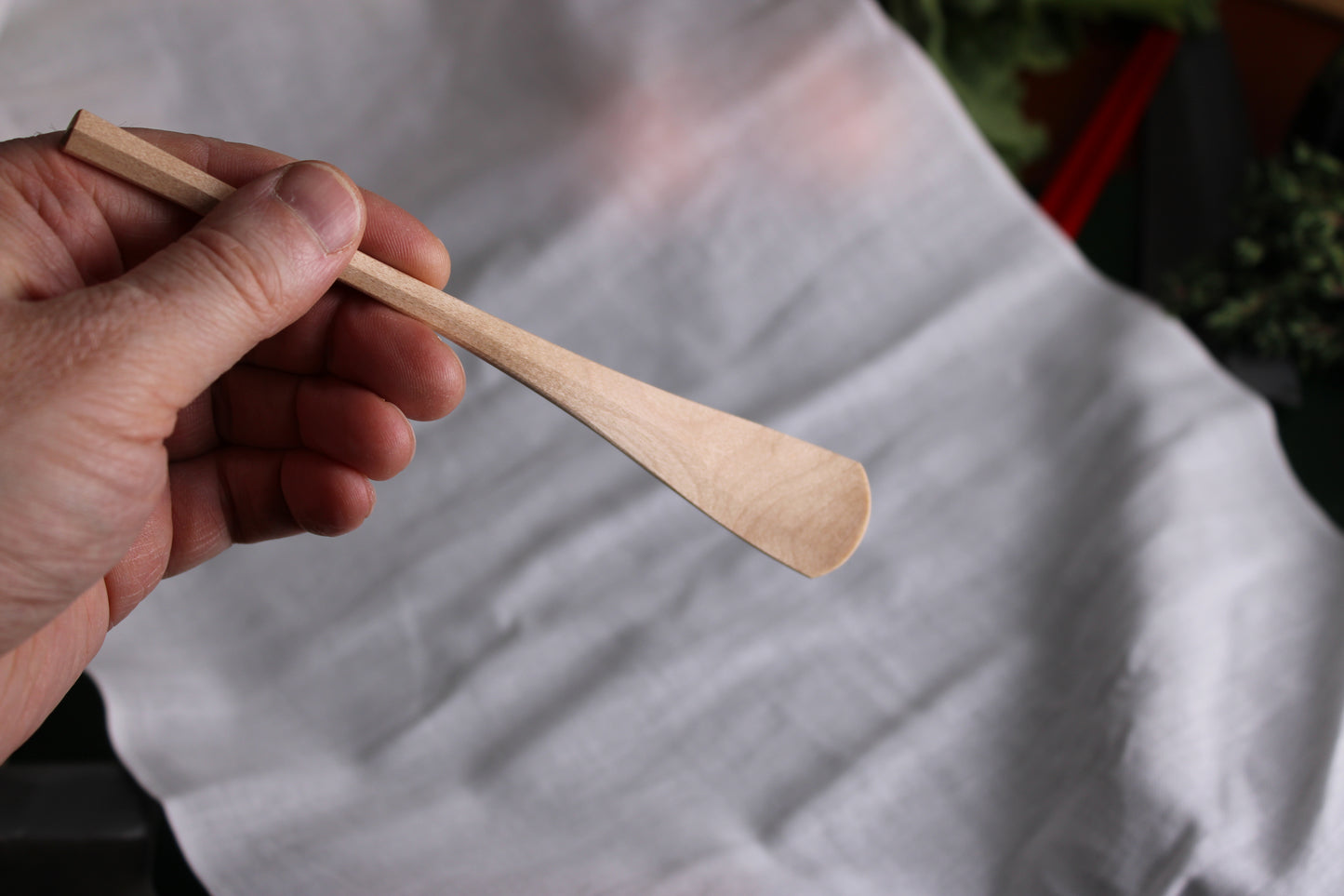 hand holding okubo house maple wood spoon with white background