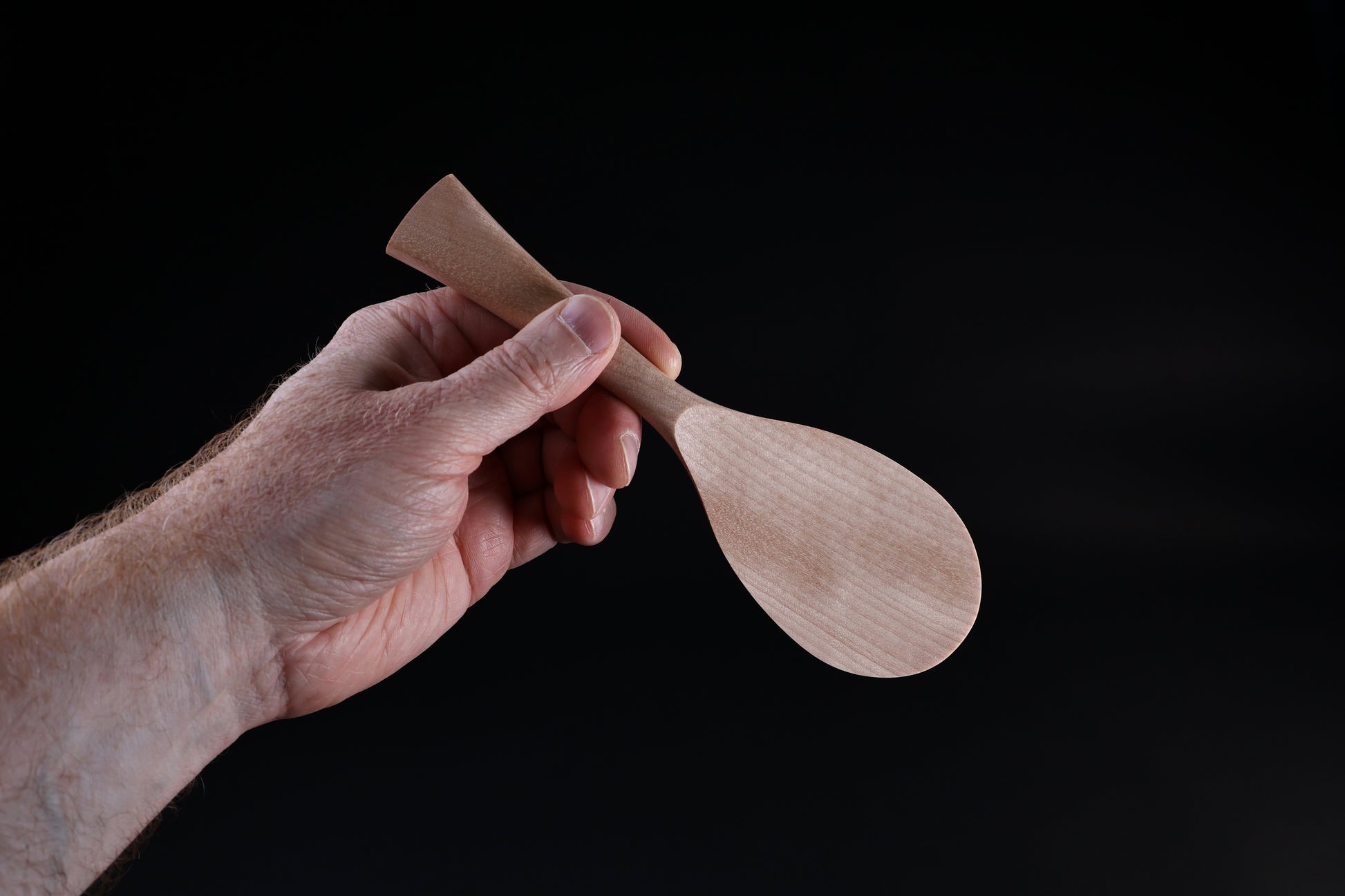 Azmaya handmade rice paddle held in hand showing size and tapered handle shape