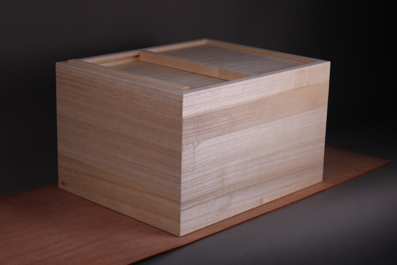 handmade paulownia wood rice container made by azmaya 5kg capacity with sliding door closed sitting on brown strip in grey background japanese kitchenware
