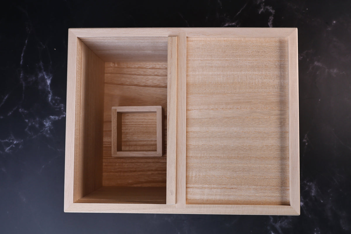 Overhead view of the Azmaya kiri wood rice bin with one side open and the masu cup inside
