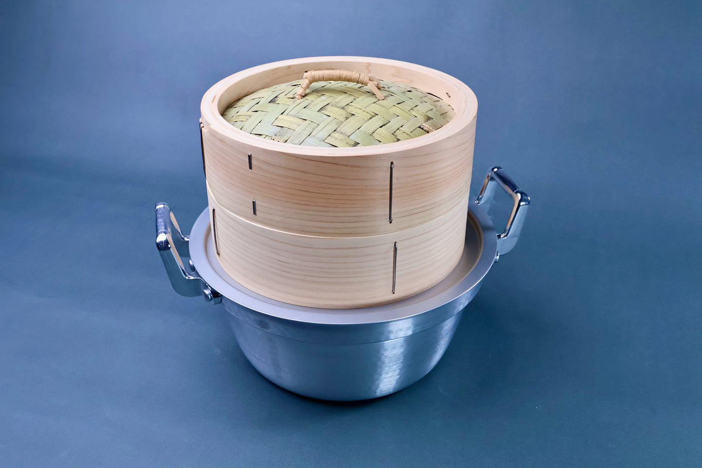 Bamboo steamer kit 21cm close front view showing woven bamboo lid, cedar body with metal staples and aluminum pot on blue background
